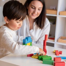 kid-playing-with-wood-blocks-and-teacher-educador-help-.jpg